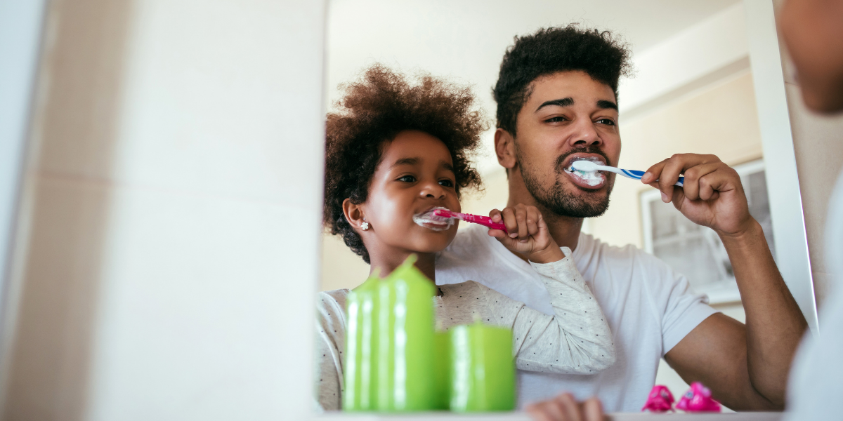 Father teaching daughter healthy dental habits.
