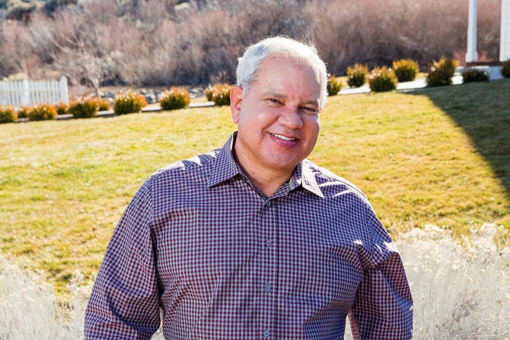 Elderly man with dental implants standing outside on green lawn